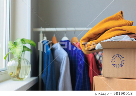 recycling, old clothes in cardboard box. textiles, paper at home and hand over 98190018