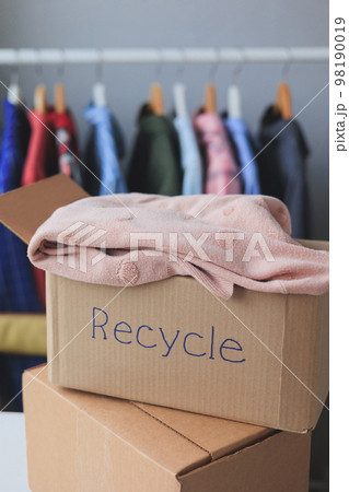 recycling, old clothes in cardboard box. textiles, paper at home and hand over 98190019