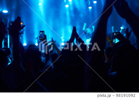 People taking photographs with smart phone during a music festival. Fans enjoying rock concert with light. People taking photographs with smart phone during a music festival. Fans enjoying rock concert with light. 98191092