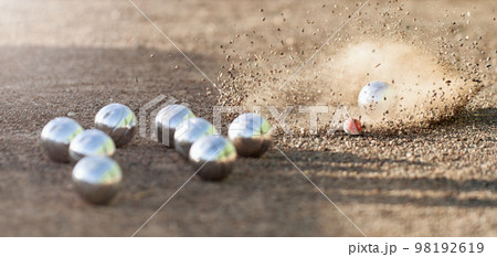 Petanque ball boules bowls on a dust floor, photo in impact. Game of petanque on the ground. Balls and a small wood jack 98192619