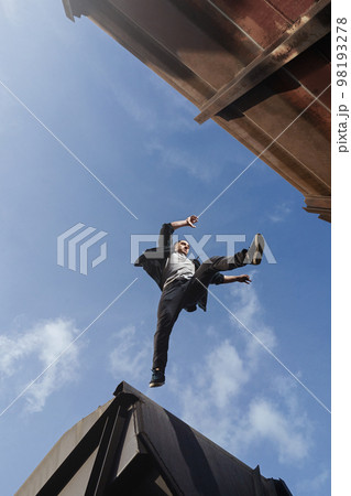 Man doing scary jump between roofs. Guy practicing parkour  98193278