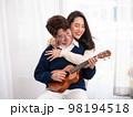 Young Asian lesbian couple intending to play a musical instrument together, guitar and kalimba, in the living room at home, the lifestyle of couple LGBT loving women happy in romantic love and fun 98194518