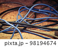 Cable power cords in a tangled mess on floor of workplace, used dirty electric outlet 98194674