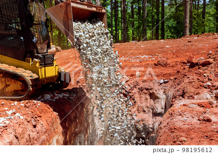 Excavator machine working on construction areas unloading a stone gravel 98195612