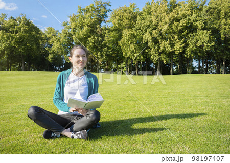 Young pretty woman on the lawn with a book in their hands. Education and knowledge 98197407