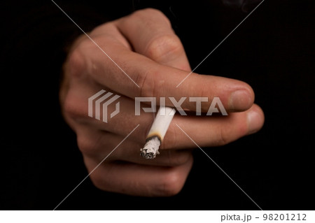 smoker holding a cigarette smoker holding a cigarette 98201212