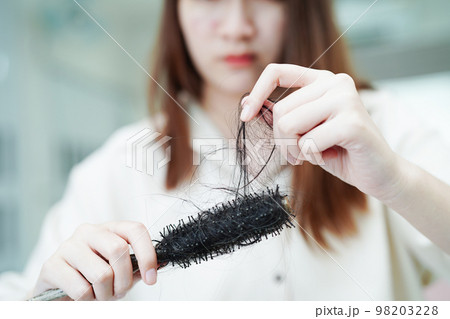 Asian woman have problem with long hair loss attach to comb brush. Asian woman have problem with long hair loss attach to comb brush. 98203228