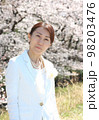 桜をバックに入学式用衣装を着て立っている40代女性　上半身 98203476