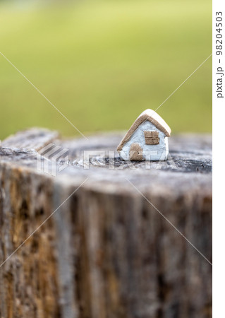 丸太の上に置いてある素焼き陶器のかわいい素朴な小さなおうち 98204503