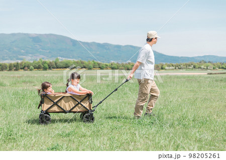 アウトドア・公園・草原でキャリーカート・ワゴンに乗って遊ぶ子供（女の子・キャンプ・パパ）の写真素材 [98205261] - PIXTA