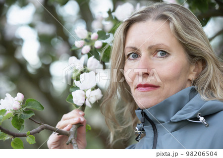 Close-up portrait of happy elderly beautiful woman posing in spring blooming park Close-up portrait of happy elderly beautiful woman posing in spring blooming park 98206504