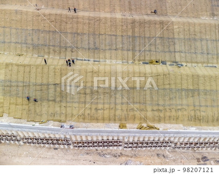 Mountain road constraction. Workers reinforce the slope over the new road. Road construction in progress on slope nature canyon. Infrastructure development and logistics. Aerial drone shot 98207121