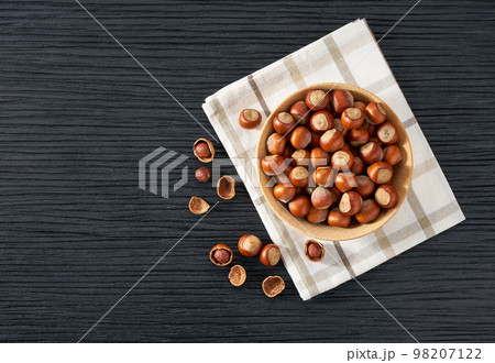 hazelnut in wooden bowl on black table with copy space. Top view 98207122