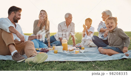 Love, picnic and family happiness with people smile and relax at a park or field, bonding and having fun. Happy kids enjoy weekend holiday with grandparents and parents, love and food in Germany 98208335