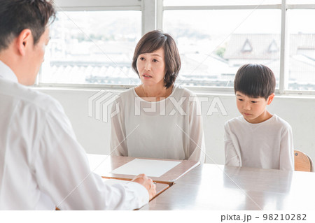学校の教室で男性教師と三者面談・個人面談する悩む親子（小学生・男の子） 98210282