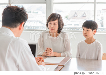 学校の教室で男性教師と三者面談・個人面談する悩む親子(小学生・男の子) 学校の教室で男性教師と三者面談・個人面談する悩む親子(小学生・男の子) 98210289