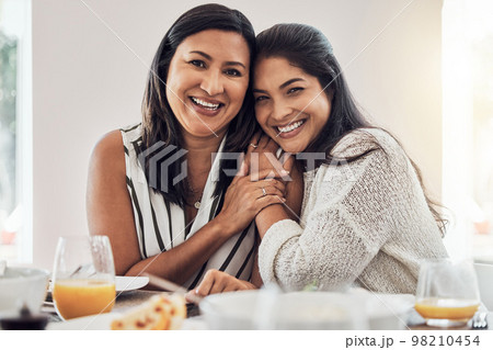 Family, love and mother with her adult daughter at home, eating food and enjoying time together. Love, bonding and lunch with a mature female sitting at a dinner table in their house 98210454