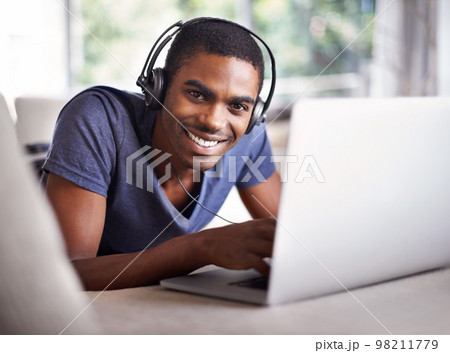Relaxing while getting some work done this weekend. a handsome young man using his laptop while relaxing at home. Relaxing while getting some work done this weekend. a handsome young man using his laptop while relaxing at home. 98211779
