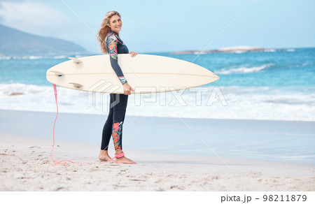 Woman, surfer and board by the ocean waves for sports exercise, hobby and swim in the summer outdoors. Portrait of a happy female standing on a beach in sport ready for surfing in South Africa 98211879