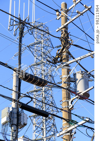 電柱と鉄塔と電線で混雑する空 98211964