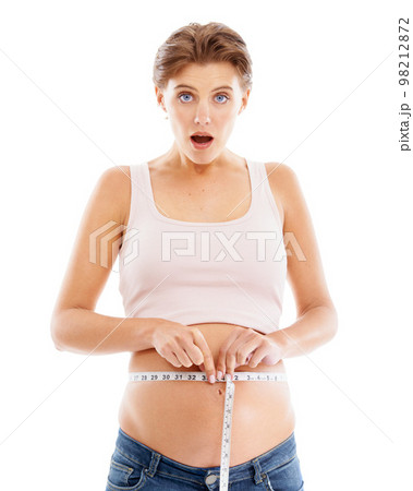 Portrait of shocked pregnant woman with measuring tape on stomach, excited smile on face and white background. Health, wellness and pregnancy, woman measuring baby growth progress in belly in studio. 98212872