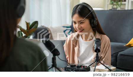 Young Asian woman use microphones wear headphones with laptop record podcast interview for radio. 98216659