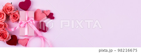 Pink roses, knitted pink and red hearts, gift box with a satin ribbon bow on a pink background. Happy Valentine's Day, Mother's Day and birthday greeting card. Banner 98216675