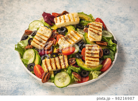 Greek style cuisine - salad with grilled halloumi cheese, avocado, pecan nuts and tomatoes. 98216987