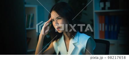 Asian business woman have a headache because using the computer and working for a long time at night 98217658