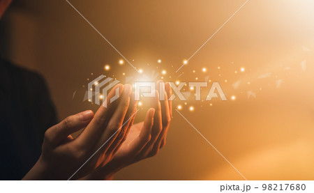 Hand praying with magic light that flows through on orange bokeh background. Hand praying with magic light that flows through on orange bokeh background. 98217680