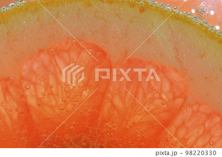 Close-up of fresh grapefruit slice on white background. Slice of red grapefruit in sparkling water on white background, close-up. Horizontal image 98220330