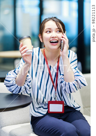オフィスで女性がスマホを使うイメージ 98221113