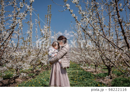 Mother holds child in blooming cherry garden 98222116