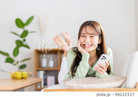 リビングでスマホを見る若い女性 リビングでスマホを見る若い女性 98222527