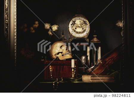 Close-up still life, Dutch painting of the 17th century. On the table on a black background are flowers, a skull, a clock, a violin, keys. Things that tell about a person's life. 98224811