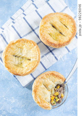 Individual beef pot pie or deep dish pie in ramekin, crust broken open, vertical, top view 98226046