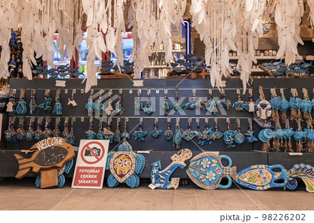 Various blue souvenirs with evil eyes hanging and arranged on wall in shop at Turkish market 98226202