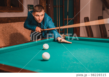 Playing billiards, a man as an amateur plays billiards, a sports board game. Playing billiards, a man as an amateur plays billiards, a sports board game. 98226515