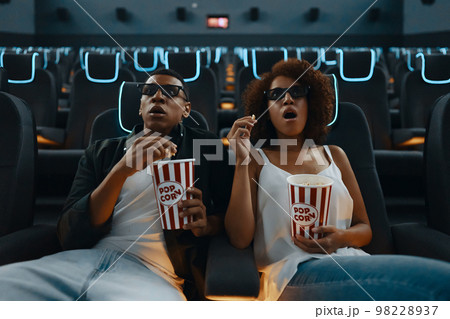A couple in love watching a movie. Watching a movie in a cinema with popcorn and 3D glasses. A couple in love watching a movie. Watching a movie in a cinema with popcorn and 3D glasses. 98228937