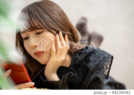 寝転んでスマホを使う若い女性 寝転んでスマホを使う若い女性 98230482