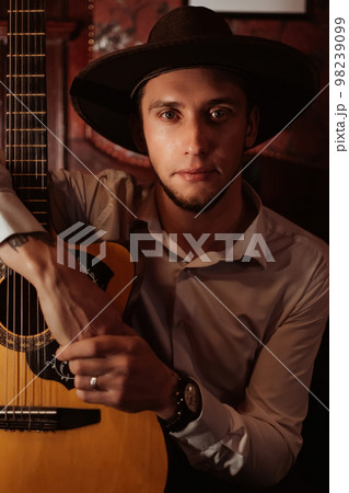 portrait of a male guitarist sitting with a guitar portrait of a male guitarist sitting with a guitar 98239099
