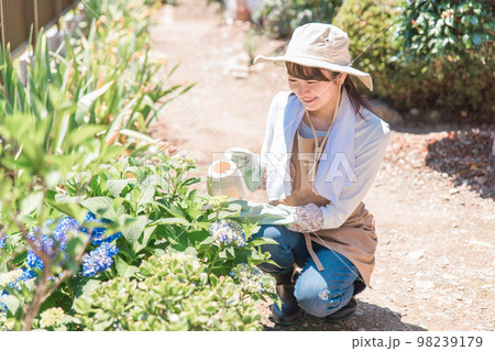 家の庭でガーデニング・園芸・家庭菜園・造園する女性(ガーデナー・水やり・エクステリア) 家の庭でガーデニング・園芸・家庭菜園・造園する女性(ガーデナー・水やり・エクステリア) 98239179