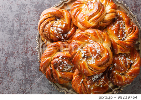 Kanelbullar or Kanelbulle is a traditional Swedish cinnamon buns flavored with cinnamon and cardamom spices and topped with pearl sugar close-up on a plate. Horizontal top view 98239764