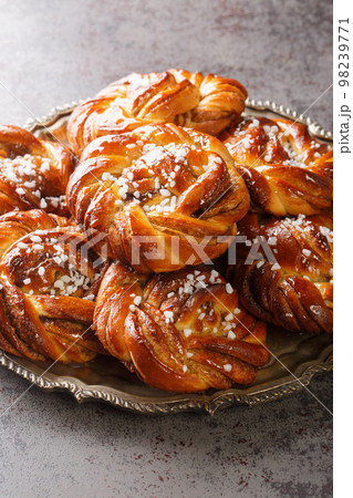 Kanelbullar Swedish cinnamon and cardamom buns with pearl sugar close-up on the plate. Vertical 98239771