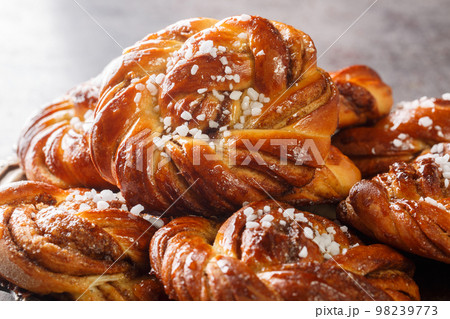 Swedish kanelbullar cinnamon buns made with a perfectly soft and chewy cardamom dough, a buttery cinnamon-sugar filling, and twisted into cute little knots close-up. Horizontal 98239773
