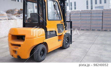 Parking forklift in logistics warehouse. Pallet stacking equipment outside and modern warehouse storage Parking forklift in logistics warehouse. Pallet stacking equipment outside and modern warehouse storage 98240052