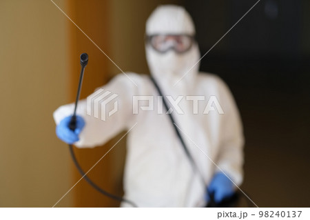 Person in protective suit spraying disinfectant closeup Person in protective suit spraying disinfectant closeup 98240137