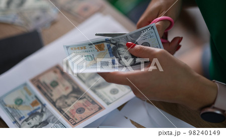 Criminal cuts dollar bills with scissors printed on printer closeup Criminal cuts dollar bills with scissors printed on printer closeup 98240149