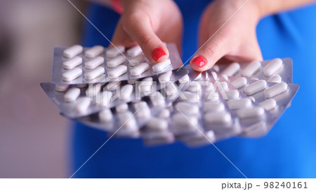 White medical round pills in metal blister in hand White medical round pills in metal blister in hand 98240161
