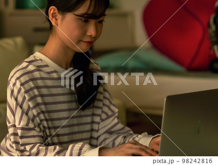 ノートパソコンを操作する若い女性　夜 98242816